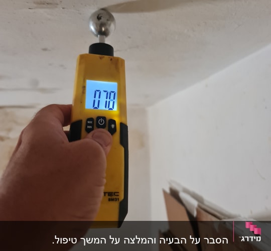בדיקת רטיבות בקיר באמצעות מד לחות אלקטרוני במהלך בדיקת מבנה